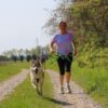 Donna che corre con il cane utilizzando la Linea CaniX con la pettorina X Run e la cintura Racing
