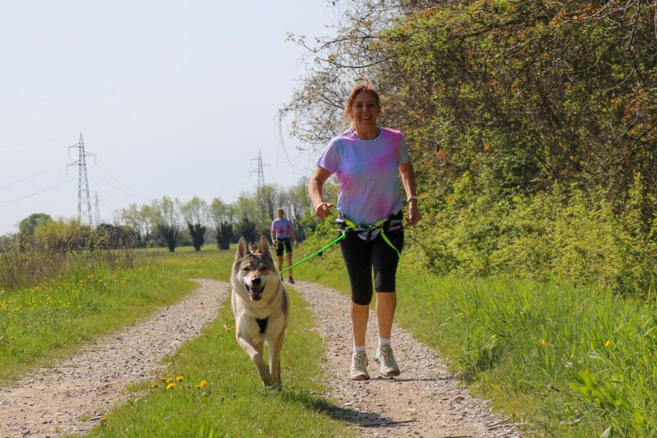 Donna che corre con il cane utilizzando la Linea CaniX con la pettorina X Run e la cintura Racing