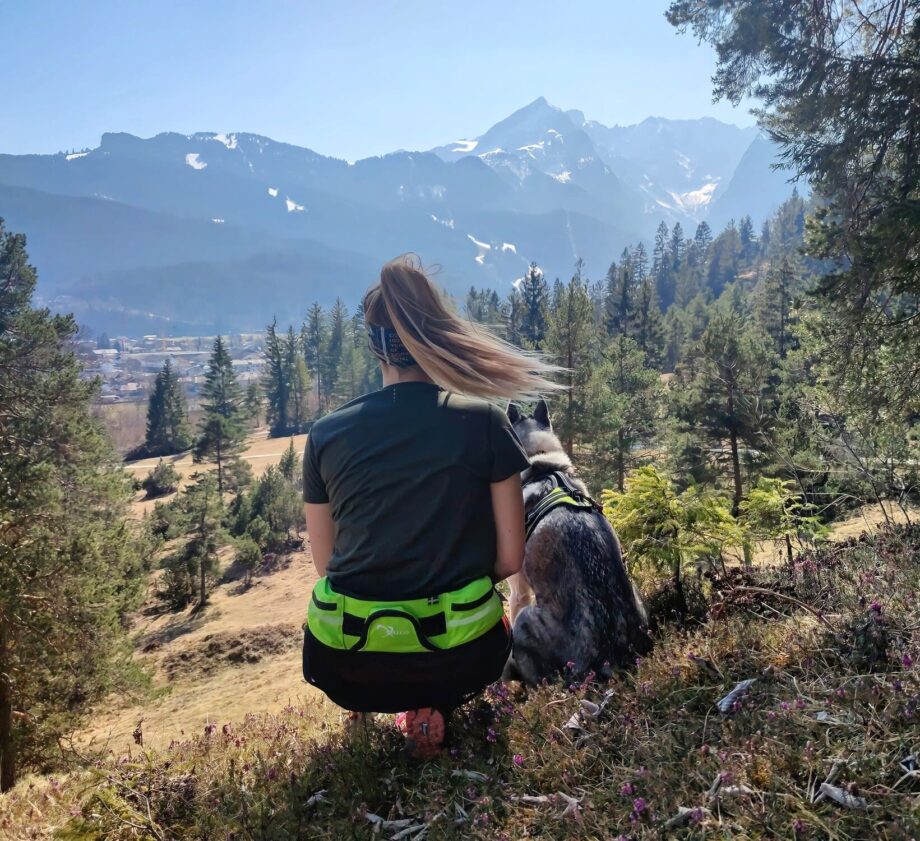 Explorer Gürtel in Aktion – Sportliche Frau geht mit Hund in den Bergen spazieren - 01